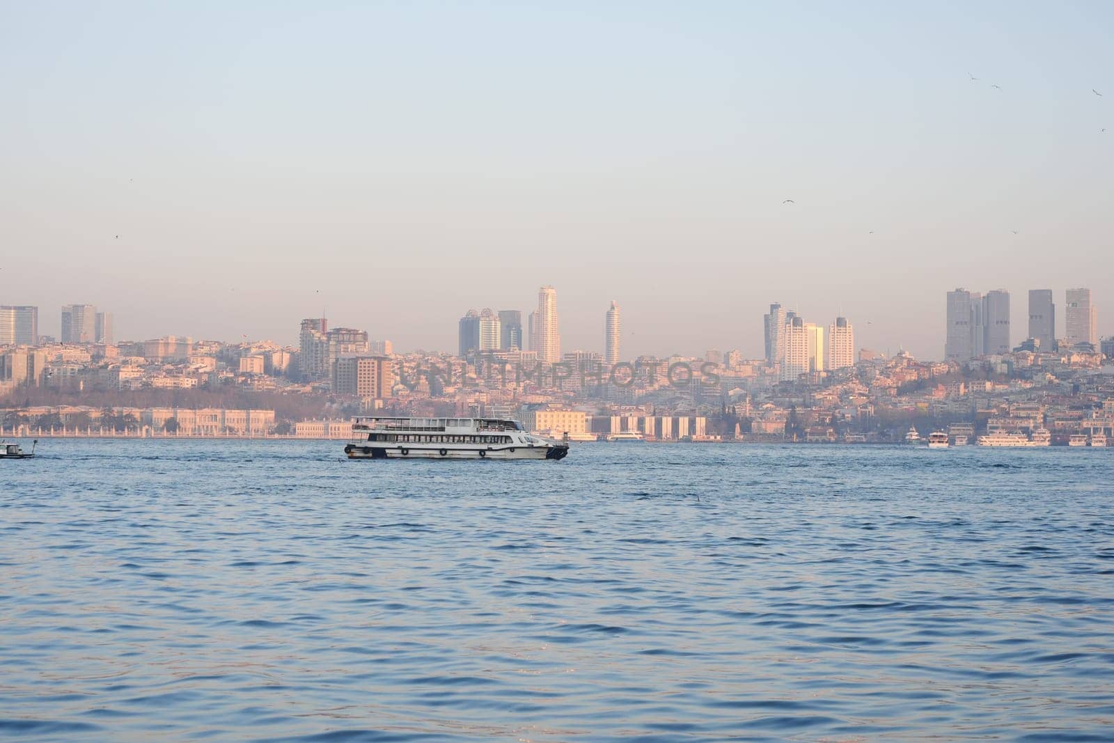 Ferry travels across the water with a city skyline glowing at dusk.