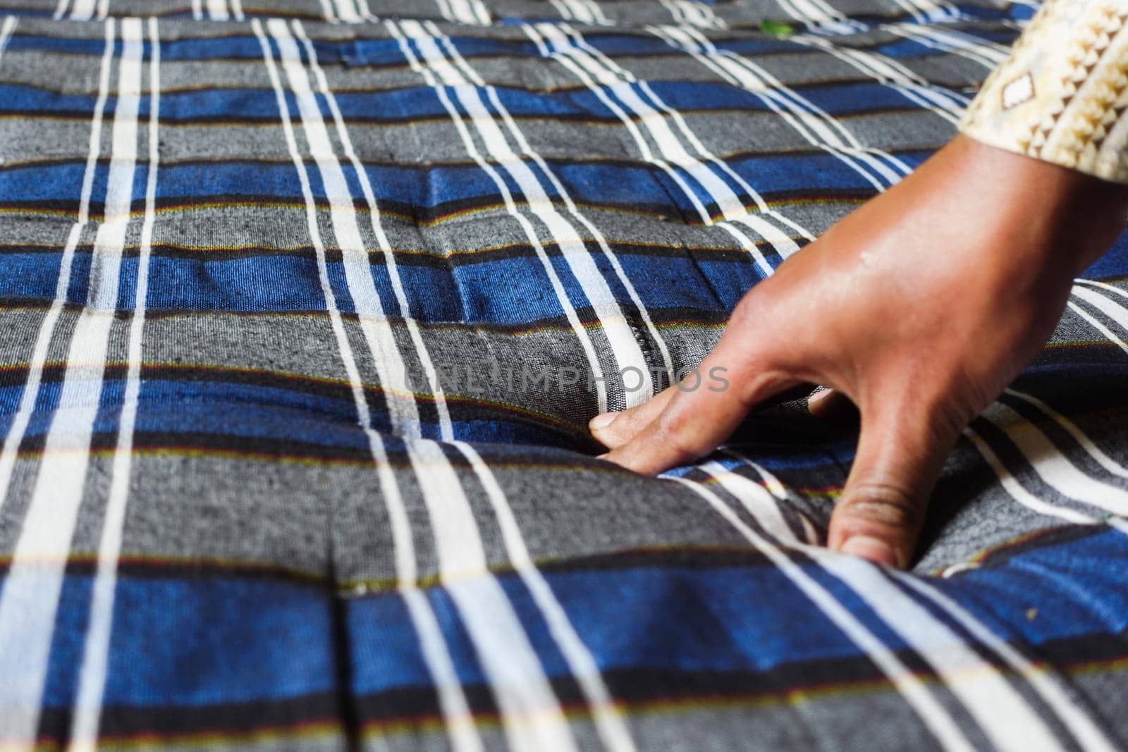 Person presses a blue and gray striped fabric to form a textured surface.
