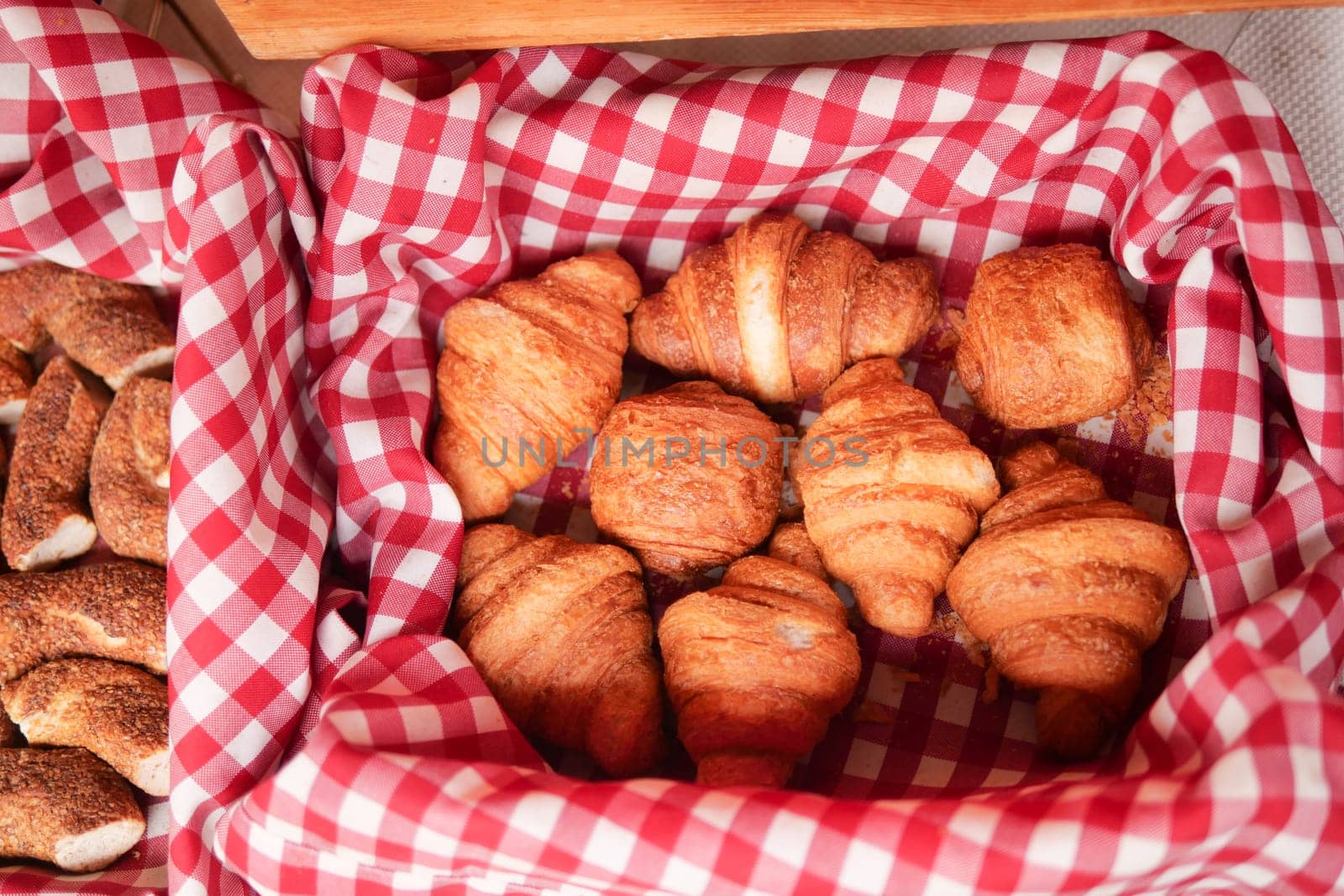 Golden-brown croissants arranged in a lined basket at an outdoor market.