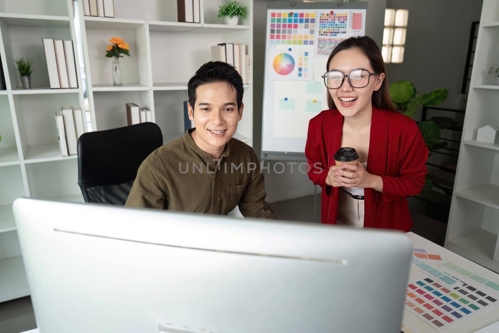 A dynamic duo of designers smiles as they review their work on the computer, celebrating a moment of teamwork and creative success.