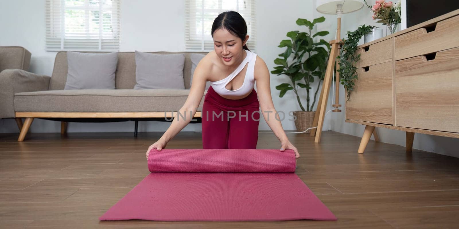 A woman rolls up her yoga mat after a session, reflecting the commitment to wellness and personal growth through mindful activities.