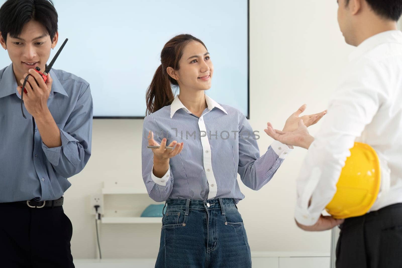 The team collaborates enthusiastically, using blueprints and digital tools for effective project planning. Their interactions highlight teamwork and innovation.