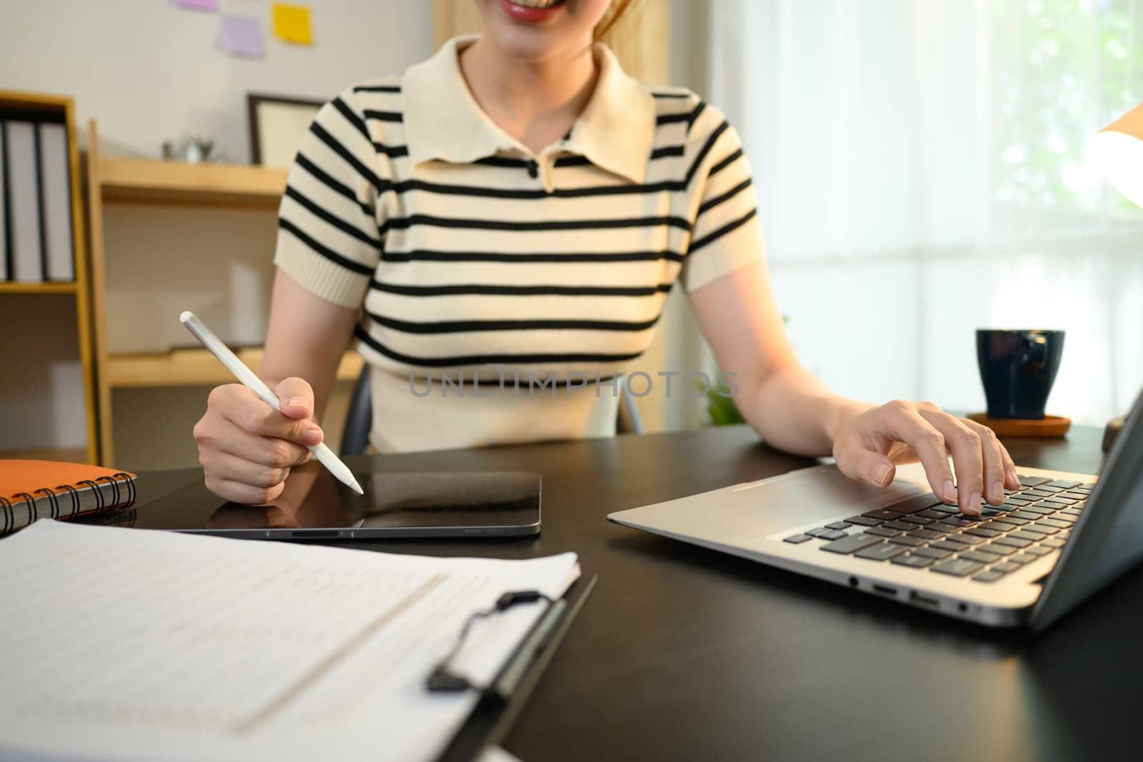 Cropped shot of smiling young woman using a stylus writing on digital tablet.