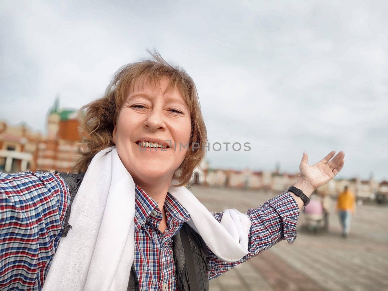 A middle-aged woman captures a joyful selfie while exploring a beautiful tourist destination during her travels.