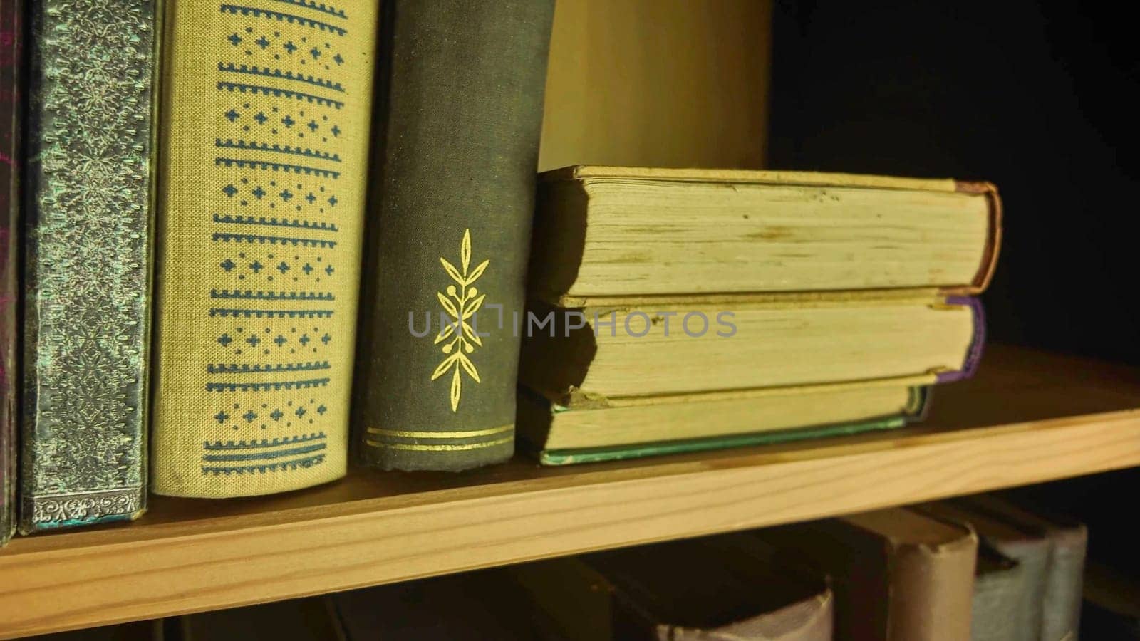 A view of two rows of very old books in the bookcase. Vintage books in an antique bookshelves. The concept of education, wisdom and love of knowledge. Close-up.