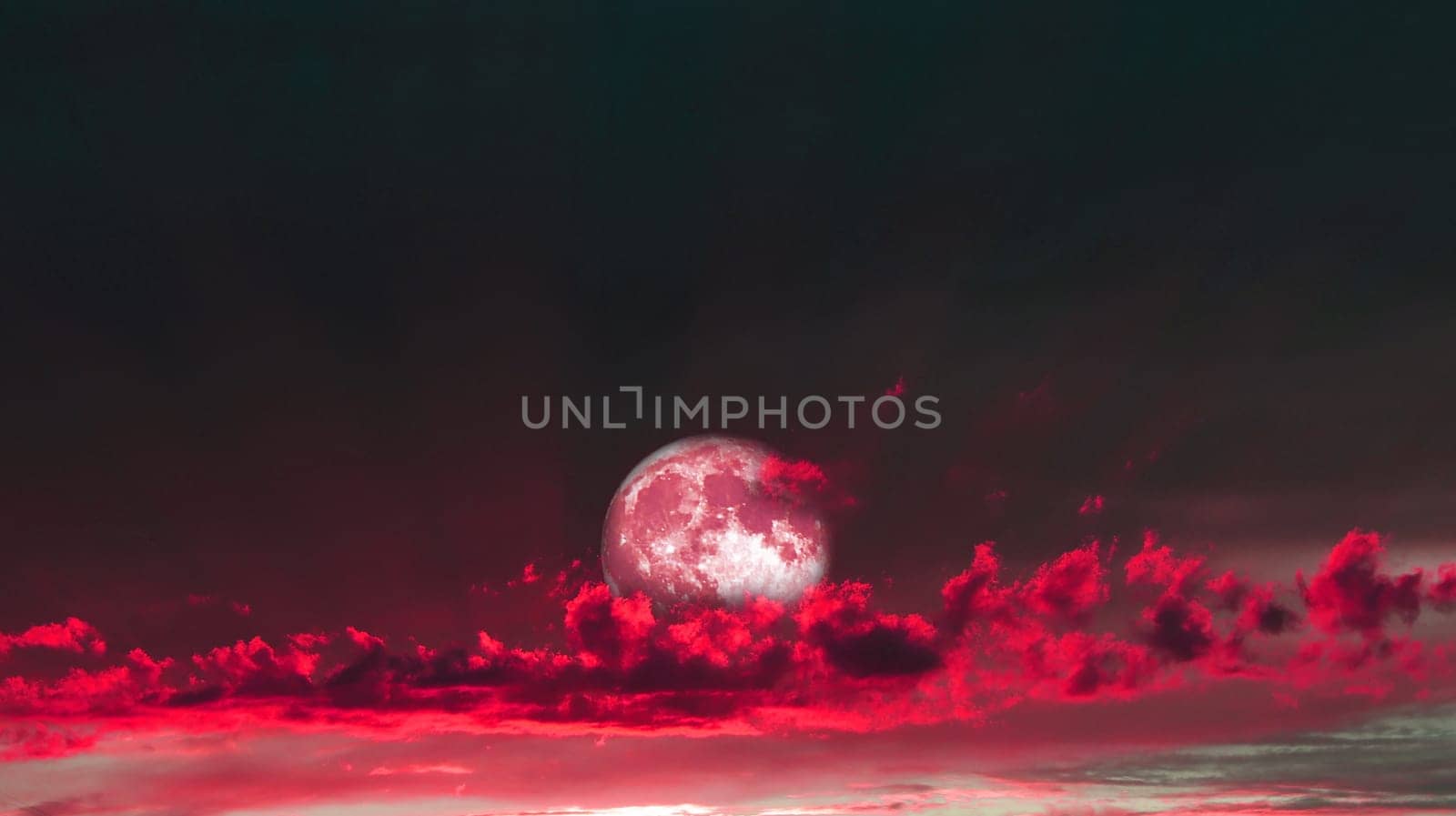 Rising full moon in a sunset with pink clouds