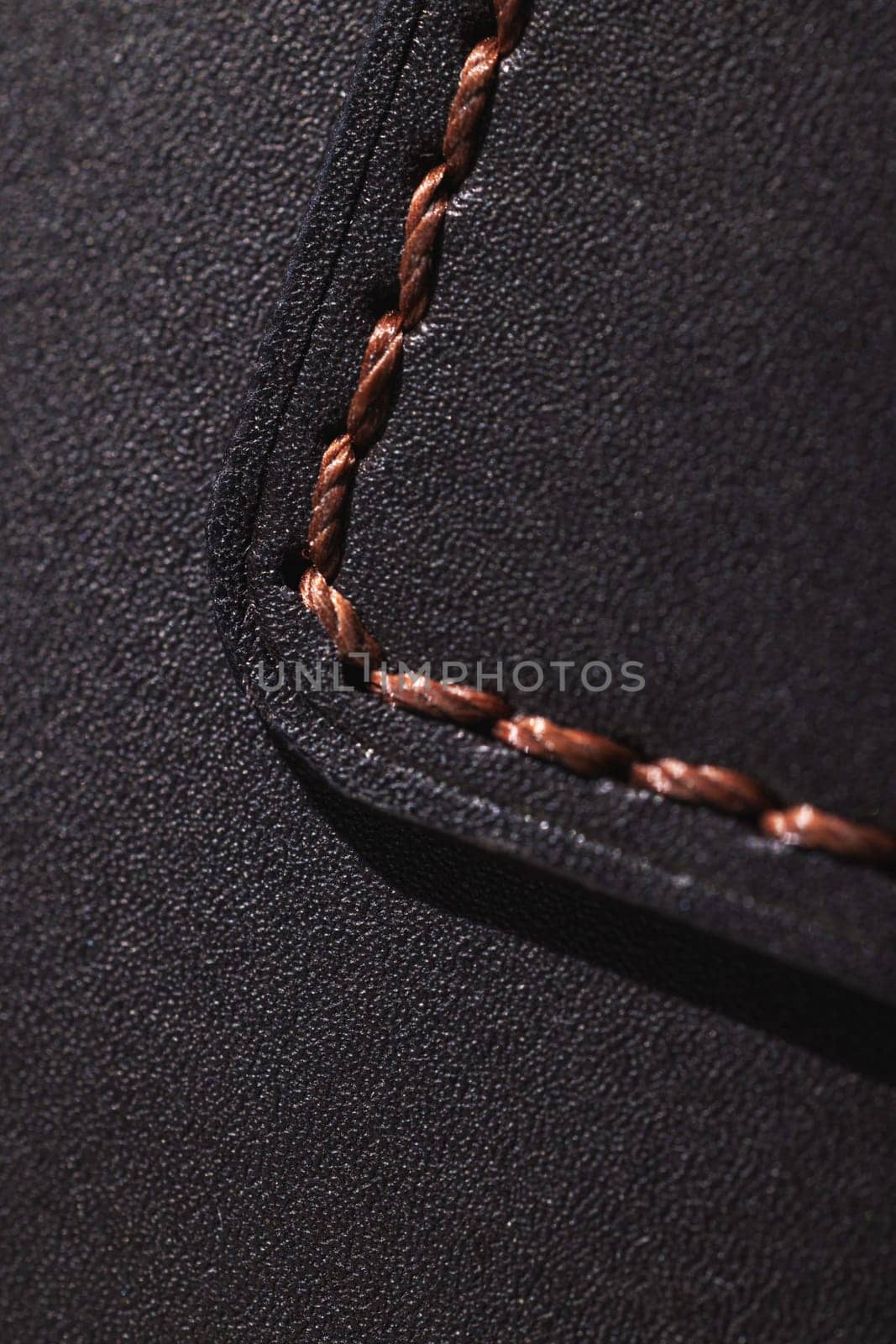 Close up showcasing brown stitching on black leather, highlighting craftsmanship and texture