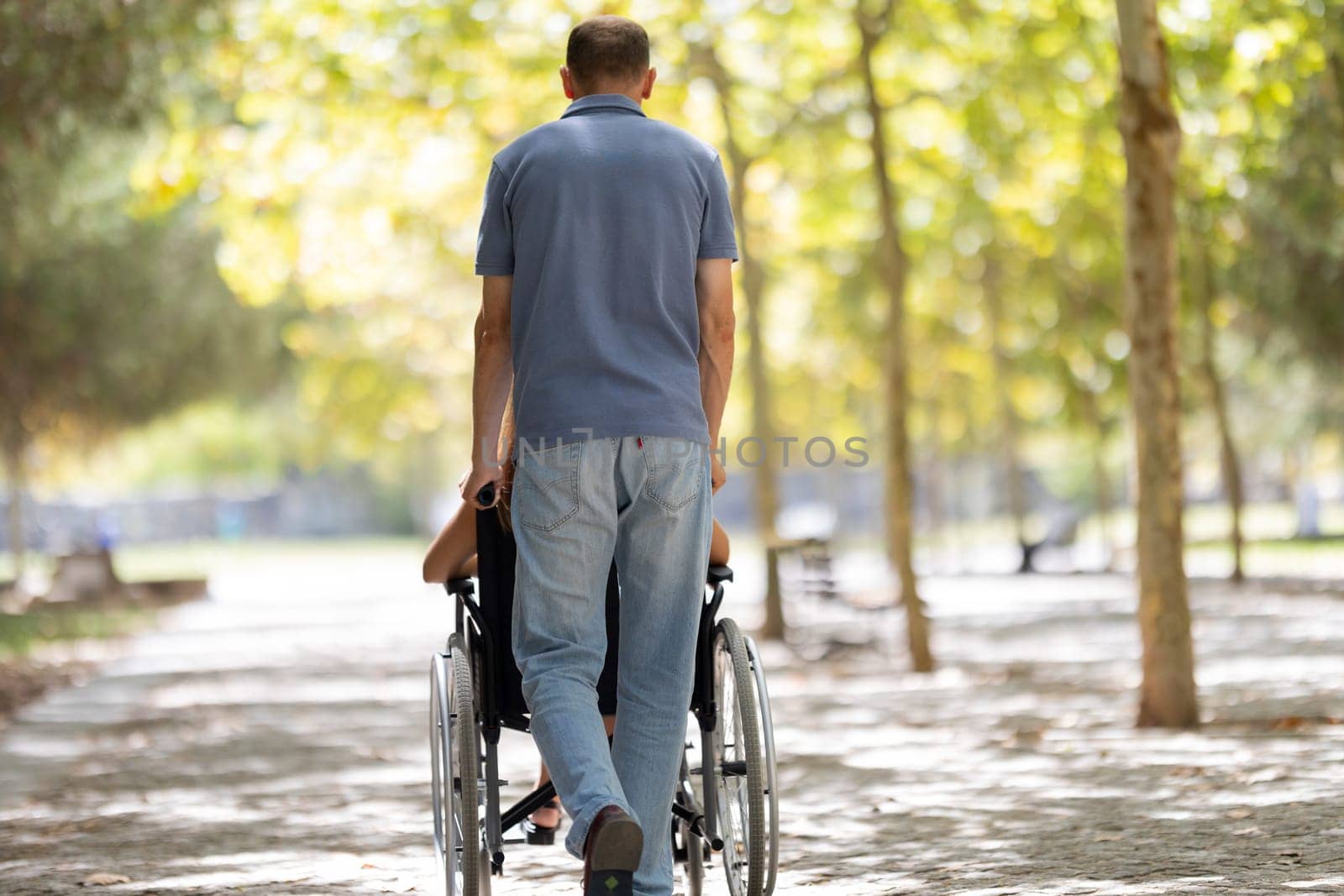 Nurse assisting a senior woman in a wheelchair, strolling through a sunny park