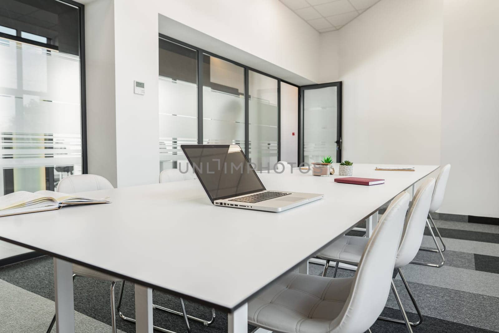 A modern laptop computer is placed on top of a white table, creating a simple and minimalist workspace in a bright room.