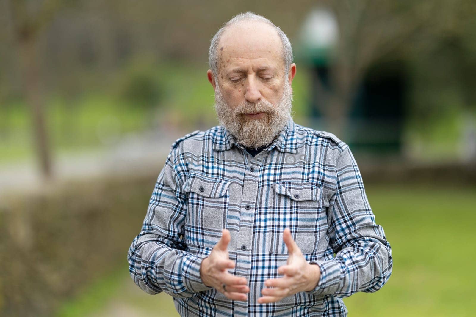 Elderly man practicing mindfulness in a green park, enjoying the tranquility of nature and connecting with his inner self