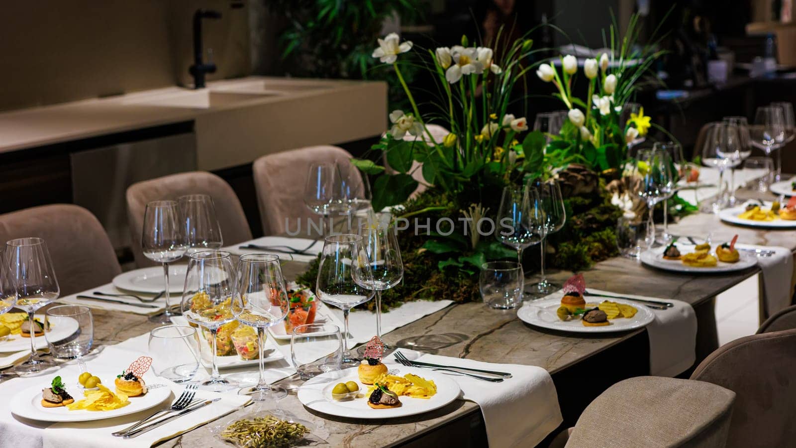 Luxurious dining table setup featuring gourmet appetizers, elegant glassware, floral centerpiece, and sophisticated decor, ideal for upscale events, weddings, banquets, and exclusive dinner parties.