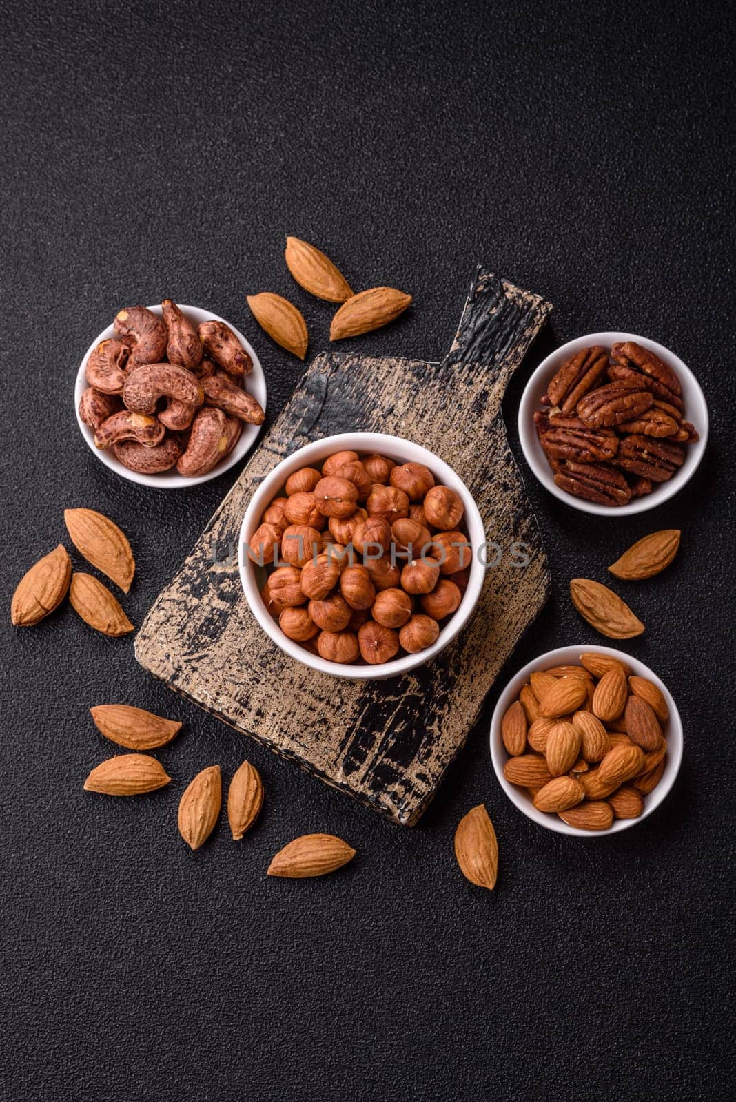 Raw hazelnuts without shells in a bowl on a dark concrete background