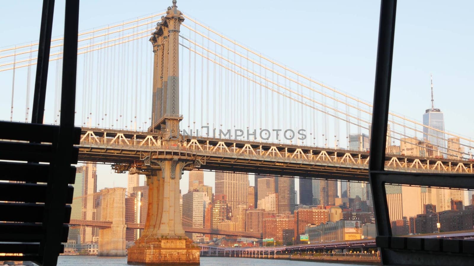 New York City, United States - 7 Sept 2023: Manhattan Bridge to Brooklyn. Pier 35 swings bench, waterfront downtown skyline cityscape. World Trade Center skyscraper, financial district morning sunset.