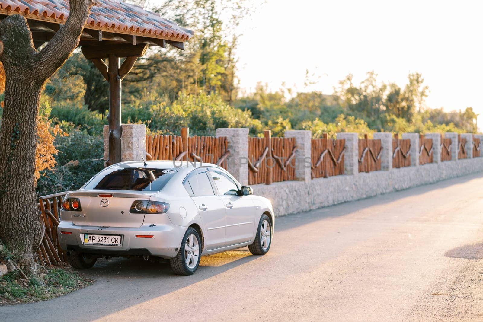 Silver car stands near a wooden fence on the road. Back view. High quality photo
