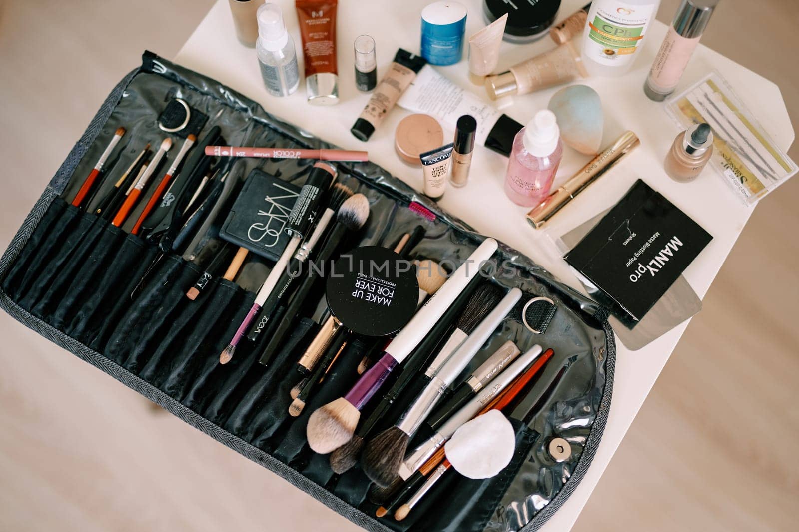 Set of makeup brushes lies on the table next to cosmetics. High quality photo