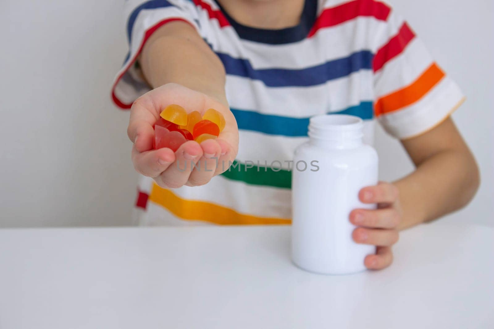 The boy eats jelly beans or takes vitamins.