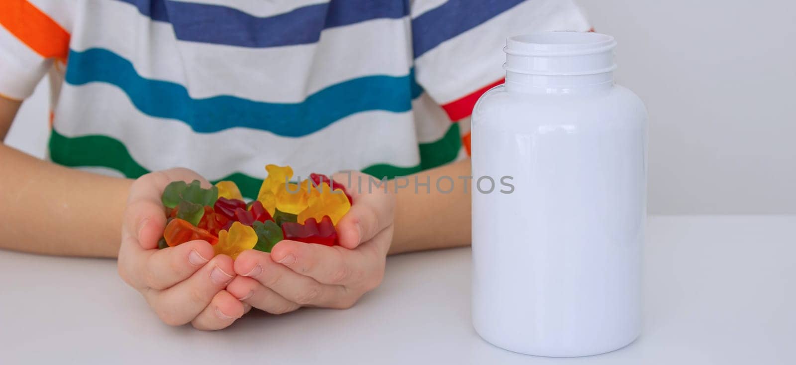 The boy eats jelly beans or takes vitamins.