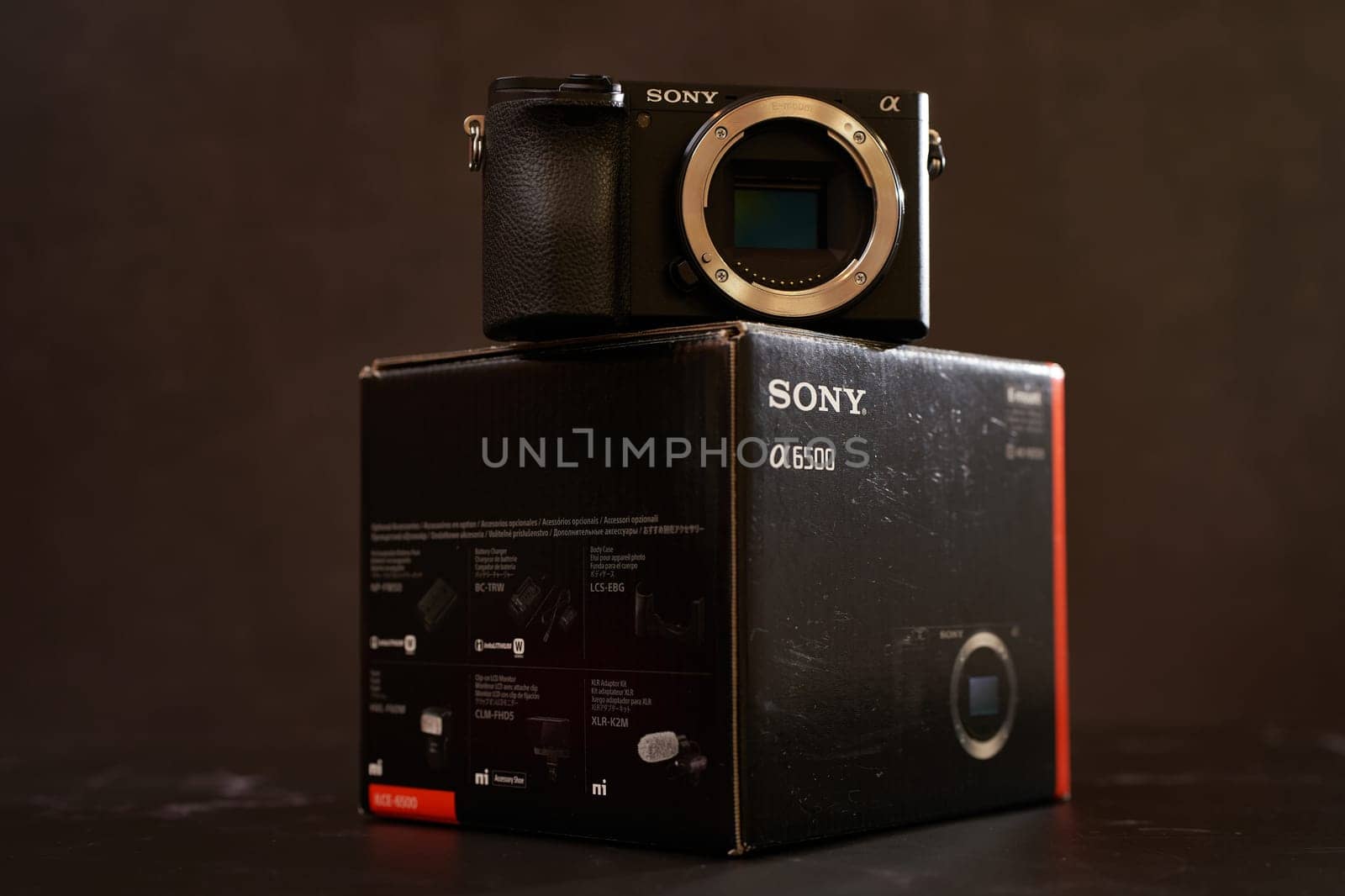 Sony A6500 mirrorless camera stands on its original packaging on a black table. High quality photo