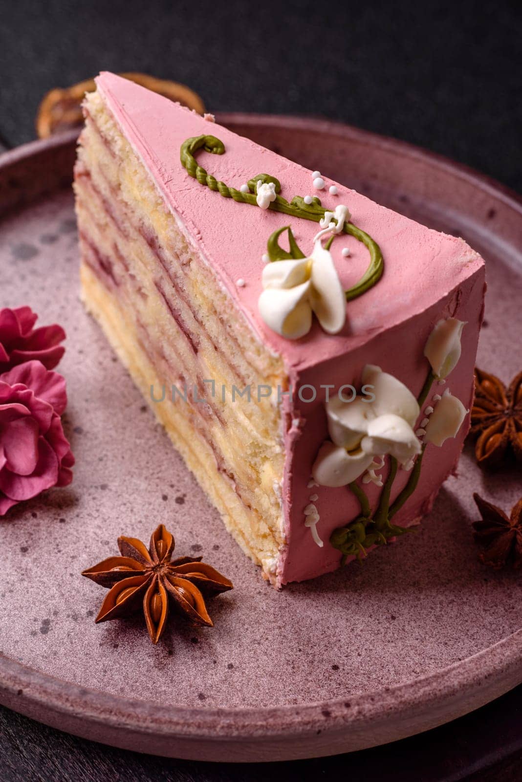 A piece of pink layered cake with strawberry flavor on a dark concrete background