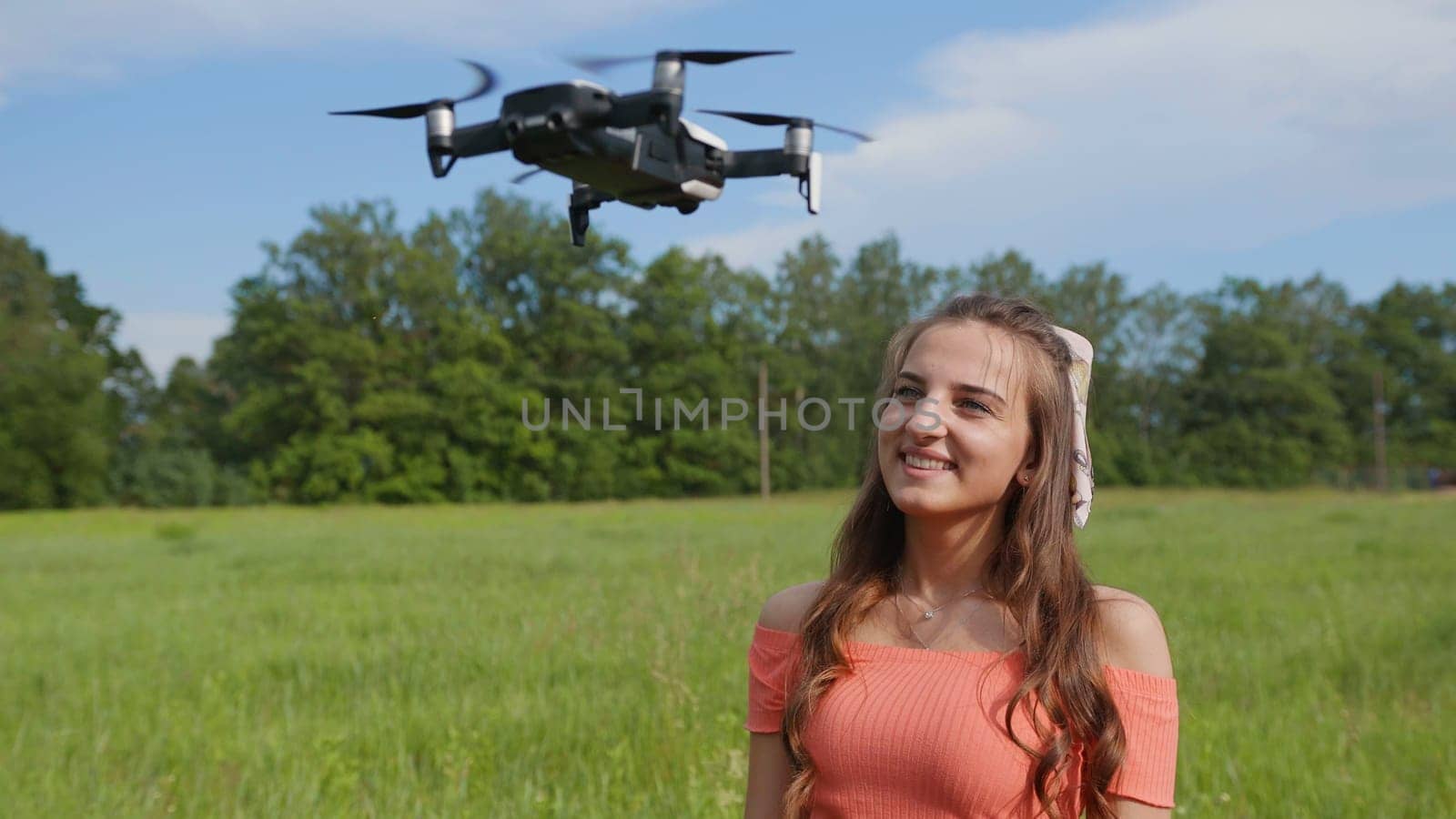 The girl watches the flight of the drone in the park