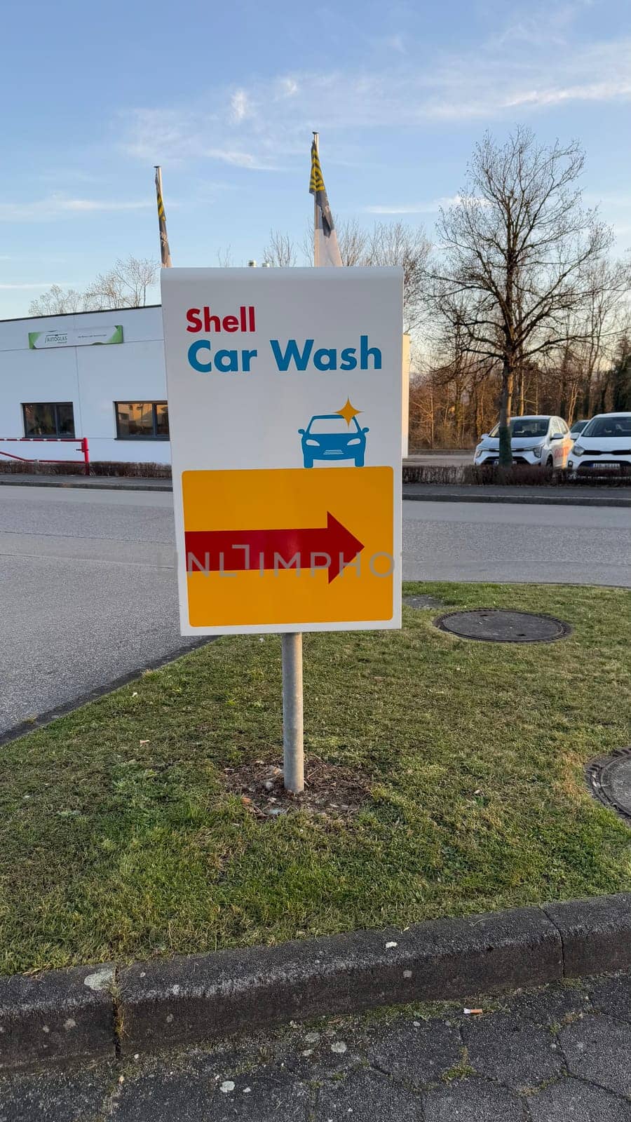 22.03.2025 Germany: Shell Gas Station Car Wash Sign With Directional Arrow. A Shell car wash sign standing on a lawn, directing vehicles with a bright arrow sign.