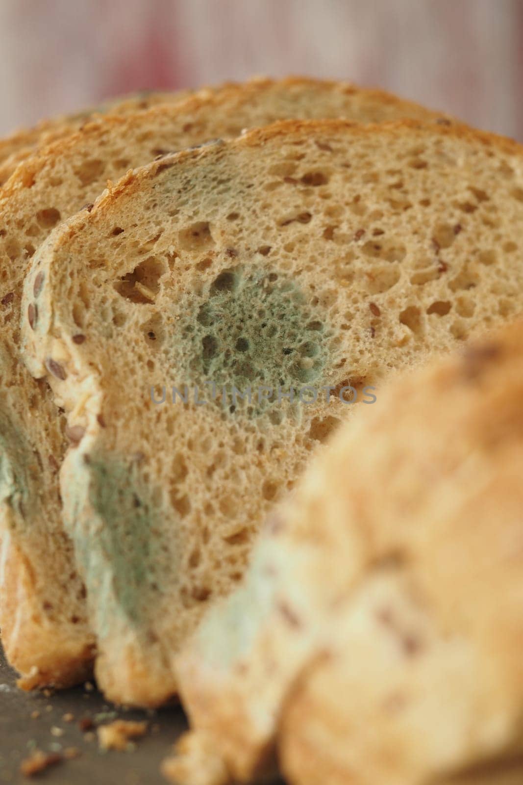 Slices of bread show mold growth, resting on a wooden surface.