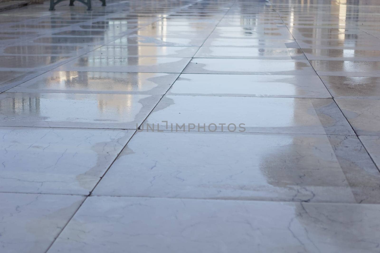 Water droplets glisten on a polished marble surface in the sunlight.
