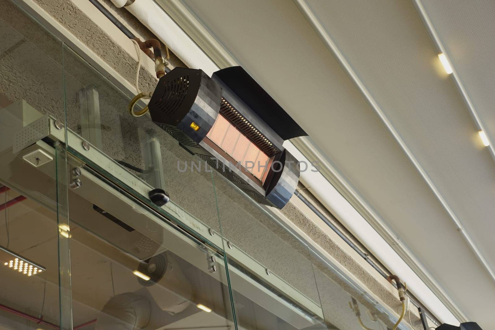 A heating unit is suspended above a glass panel, providing warmth indoors.