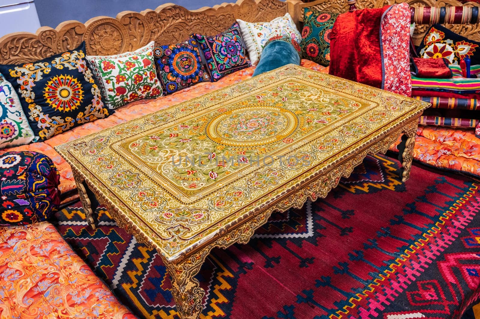 beautiful patterned traditional Uzbek dastarkhan table, colorful pillows and a vintage carpet in the interior of a house in Uzbekistan. Life and culture of Central Asia
