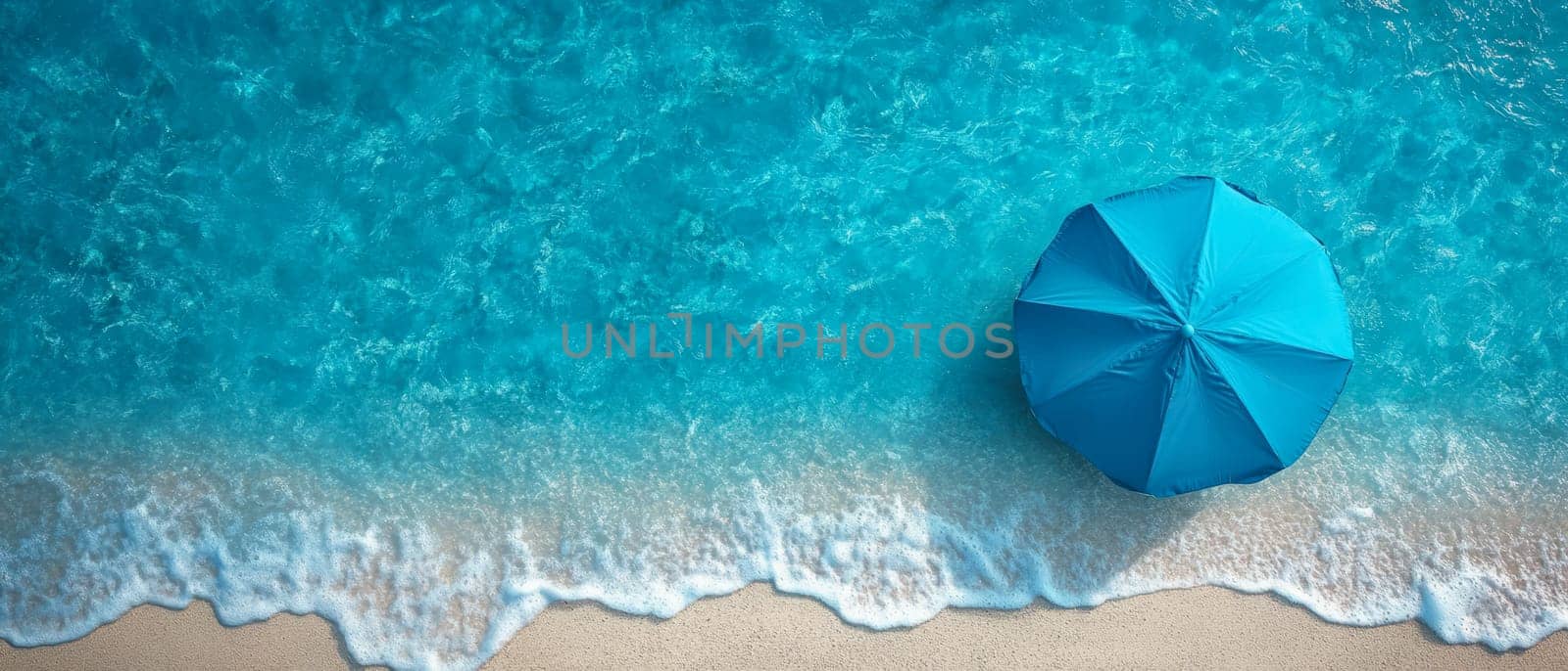 A blue beach umbrella stands near the shoreline, with ocean waves gently washing onto the sandy shore. A peaceful summer vacation scene.
