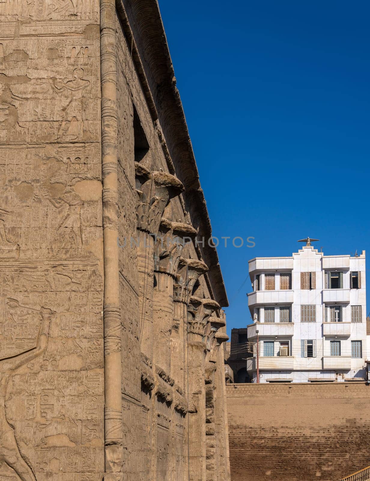 Excavations and modern buildings around the well-preserved facade of the Temple of Esna with carvings