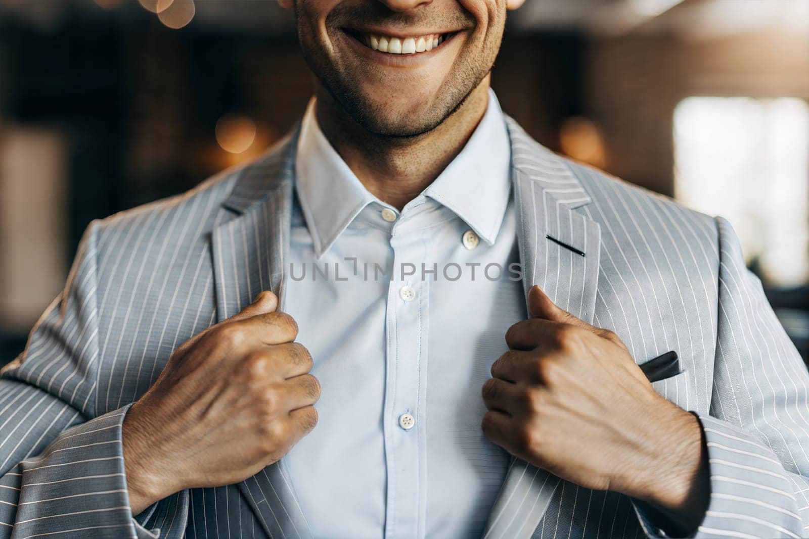 In a modern indoor space, a businessman in a striped suit smiles broadly while adjusting his jacket, exuding confidence and style. Generative AI.