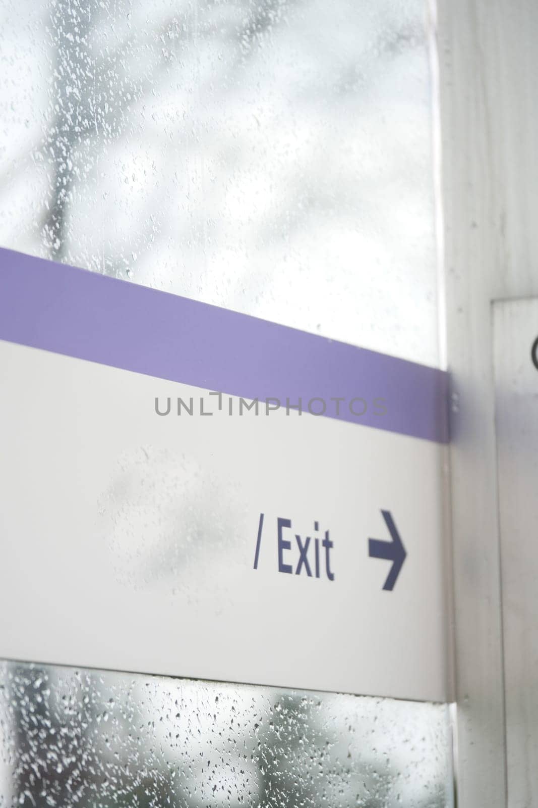 Sign directing people to the exit with raindrops on the glass.