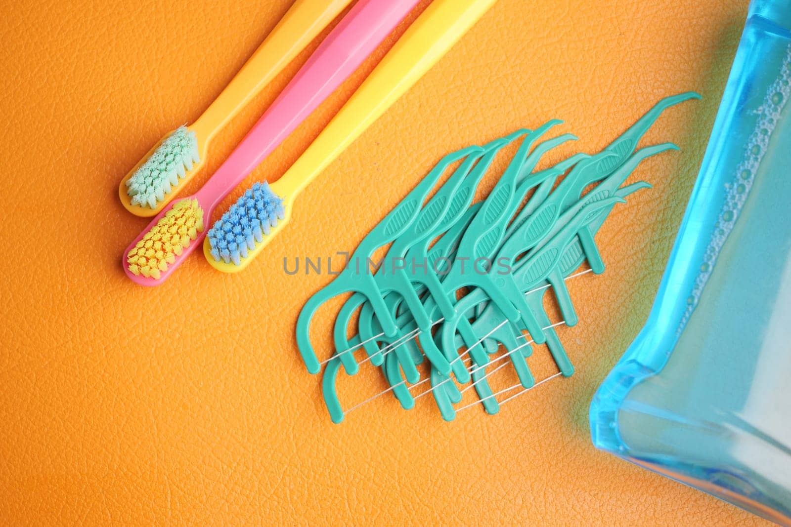Colorful toothbrushes and dental tools arranged on bright surface.