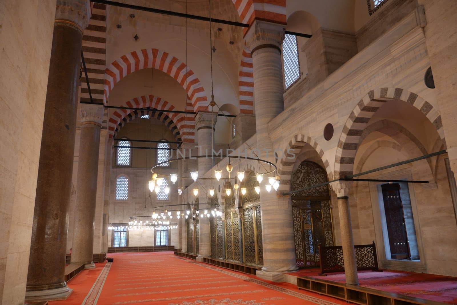 Interior view of a historic mosque showcasing arches and ornate lighting.