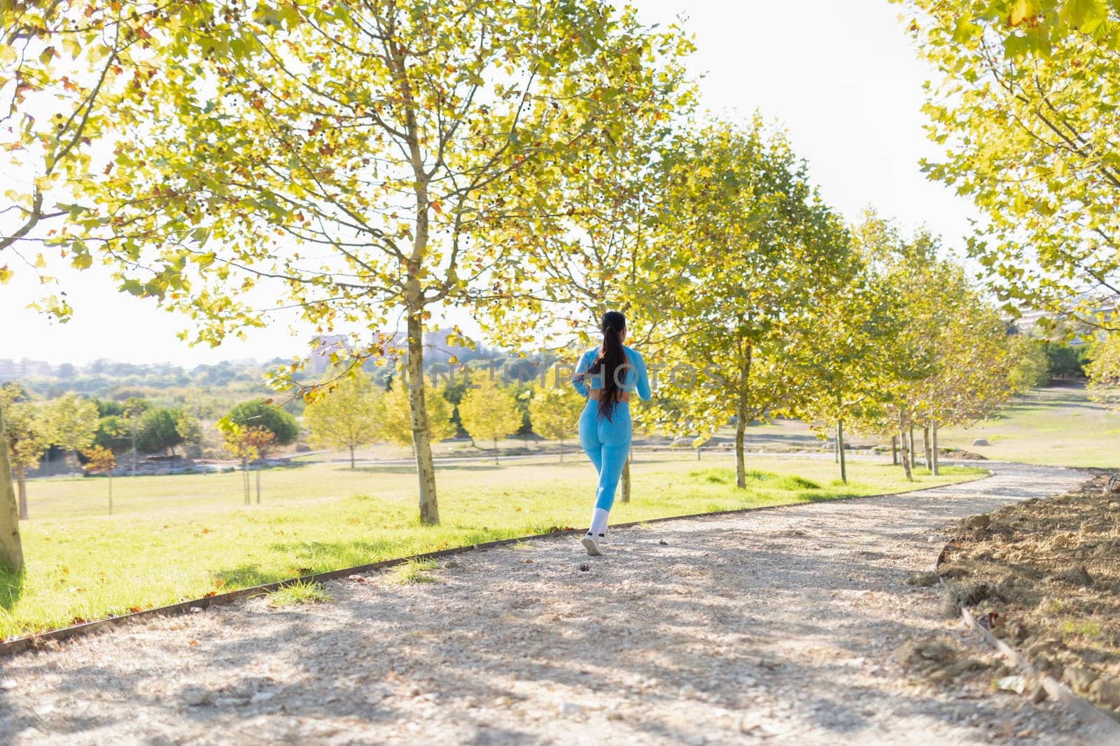Young sportswoman running in a park during a sunny autumn day