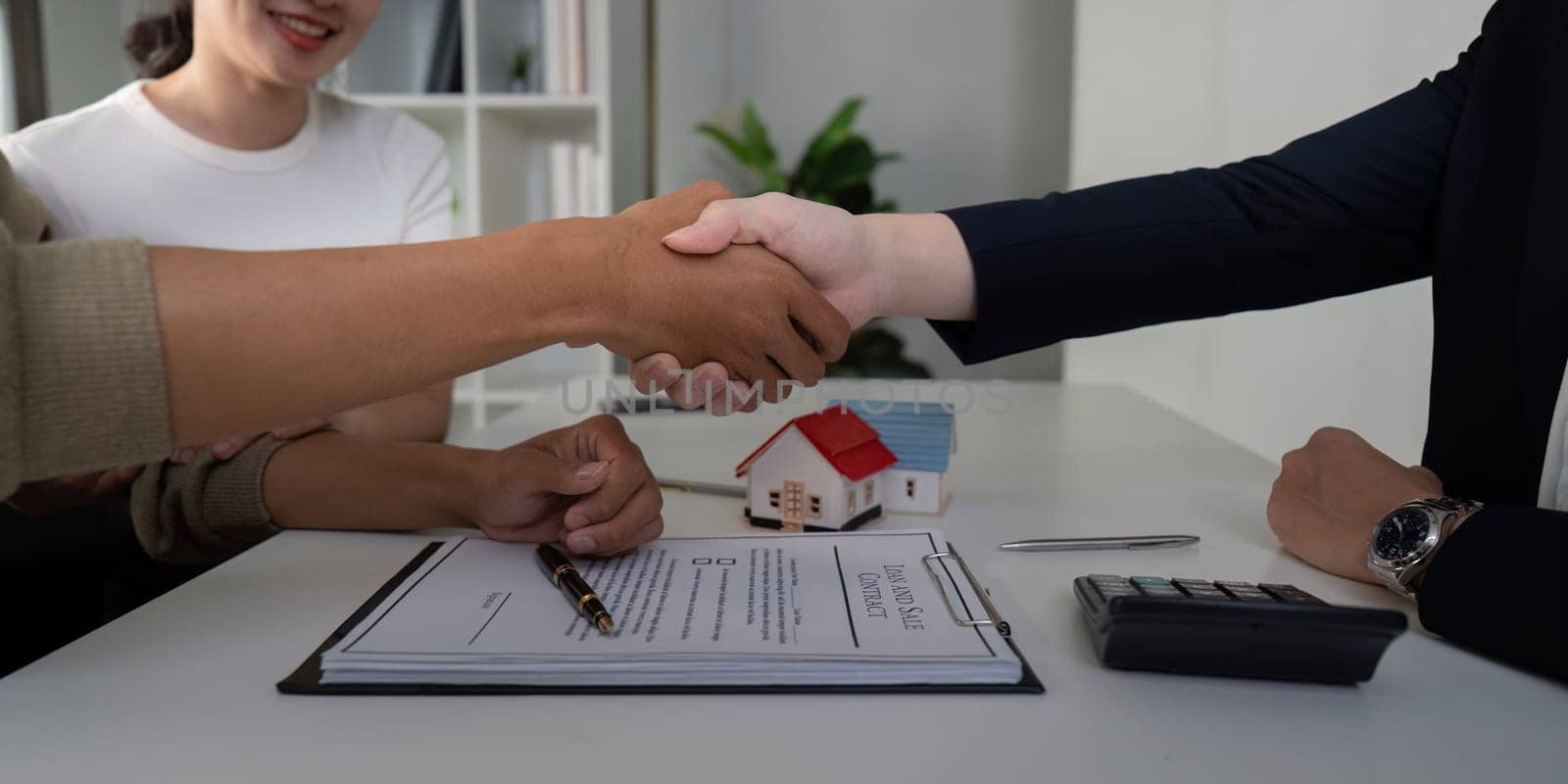 After finalizing their paperwork, the couple shakes hands with their agent, symbolizing the successful completion of their home-buying journey.