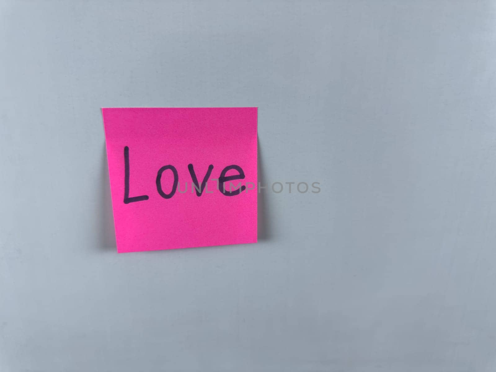 Sticky note with Love written on it, affixed to a white background. Photo represents the emotion of love and is ideal for conveying themes of romance, relationships, and personal connections