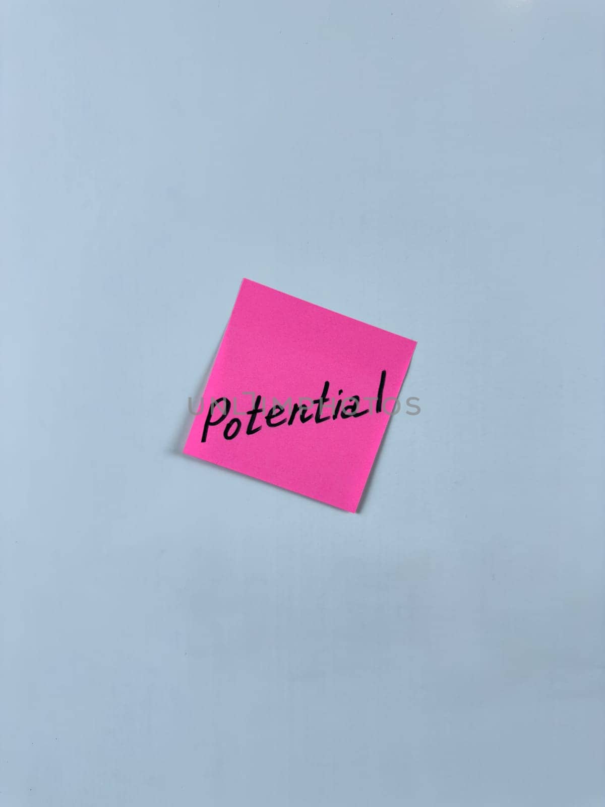 Sticky note with Potential written on it, affixed to white background. Image represents capability and opportunity, ideal for themes of potential and future growth