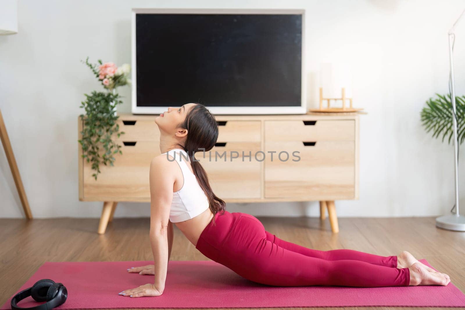 This image captures a woman performing the upward-facing dog pose, vital for building core strength and enhancing flexibility at home.