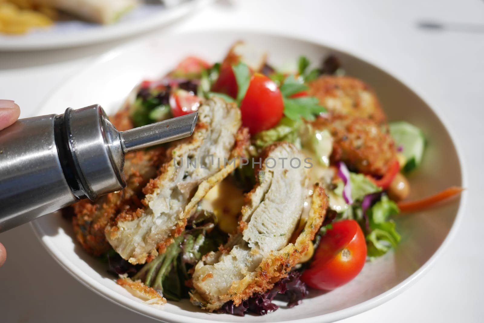 Fresh salad topped with crispy chicken and drizzle of dressing enjoyed outdoors.