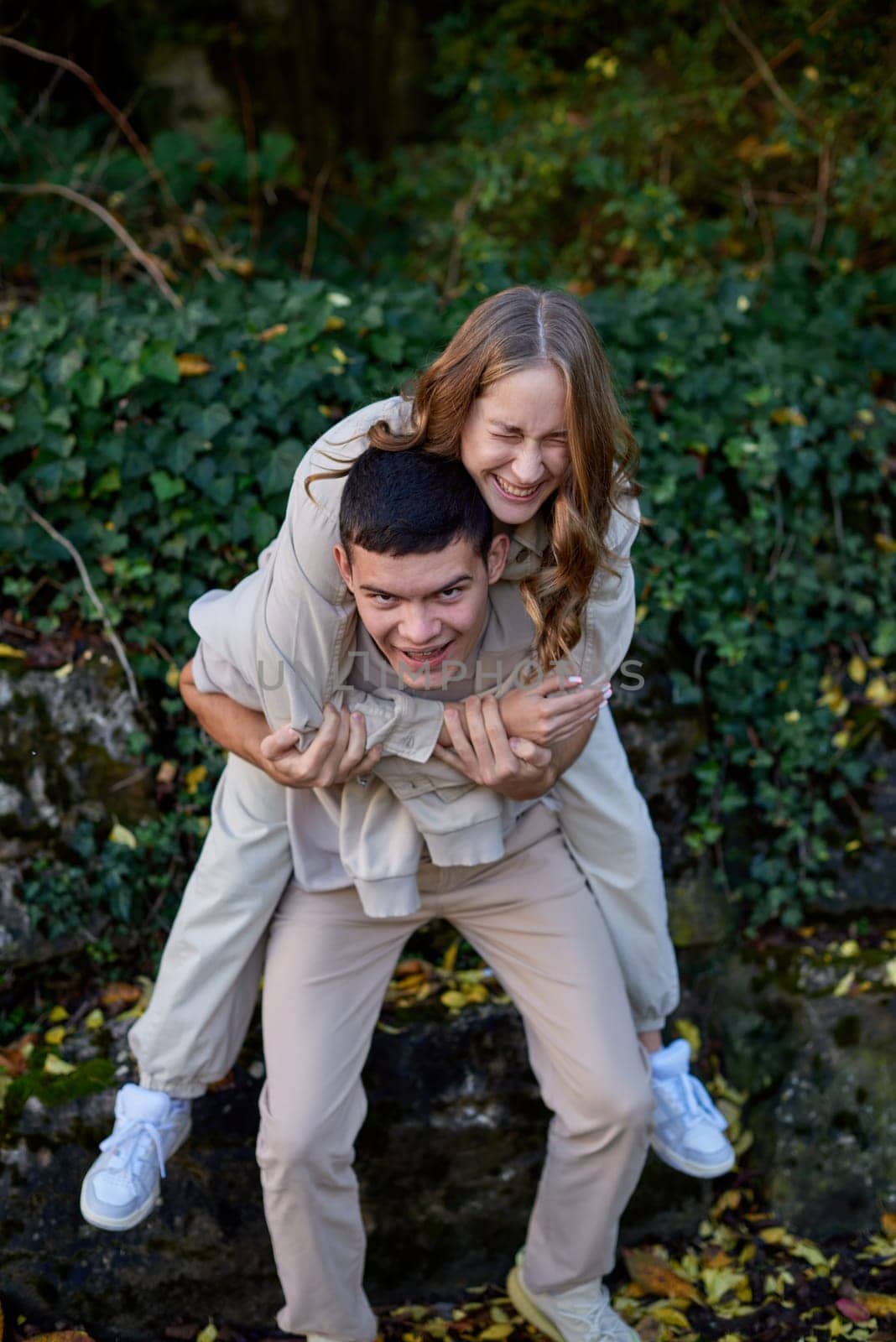 Young Cute Female Hugs Boyfriend. In Autumn Outdoor. Lovers Walking in Park. Attractive Funny Couple. Lovestory in Forest. Man and Woman. Cute Lovers in the Park. Family Concept. Happy Couple.