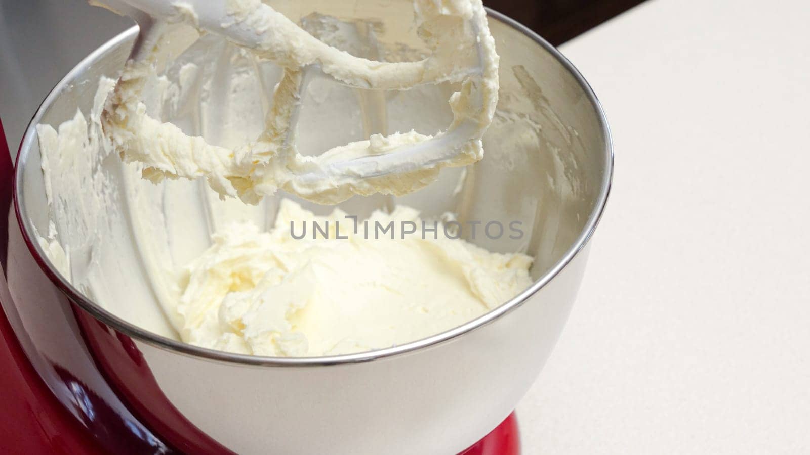 Vibrant Red Stand Mixer with Stainless Steel Bowl Mixing Yellow Batter.