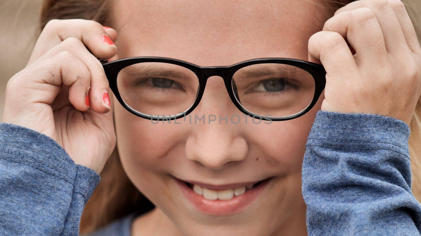 Portrait of a cheerful school girl smiling while adjusting her eyeglasses, capturing the essence of youth and the joy of learning