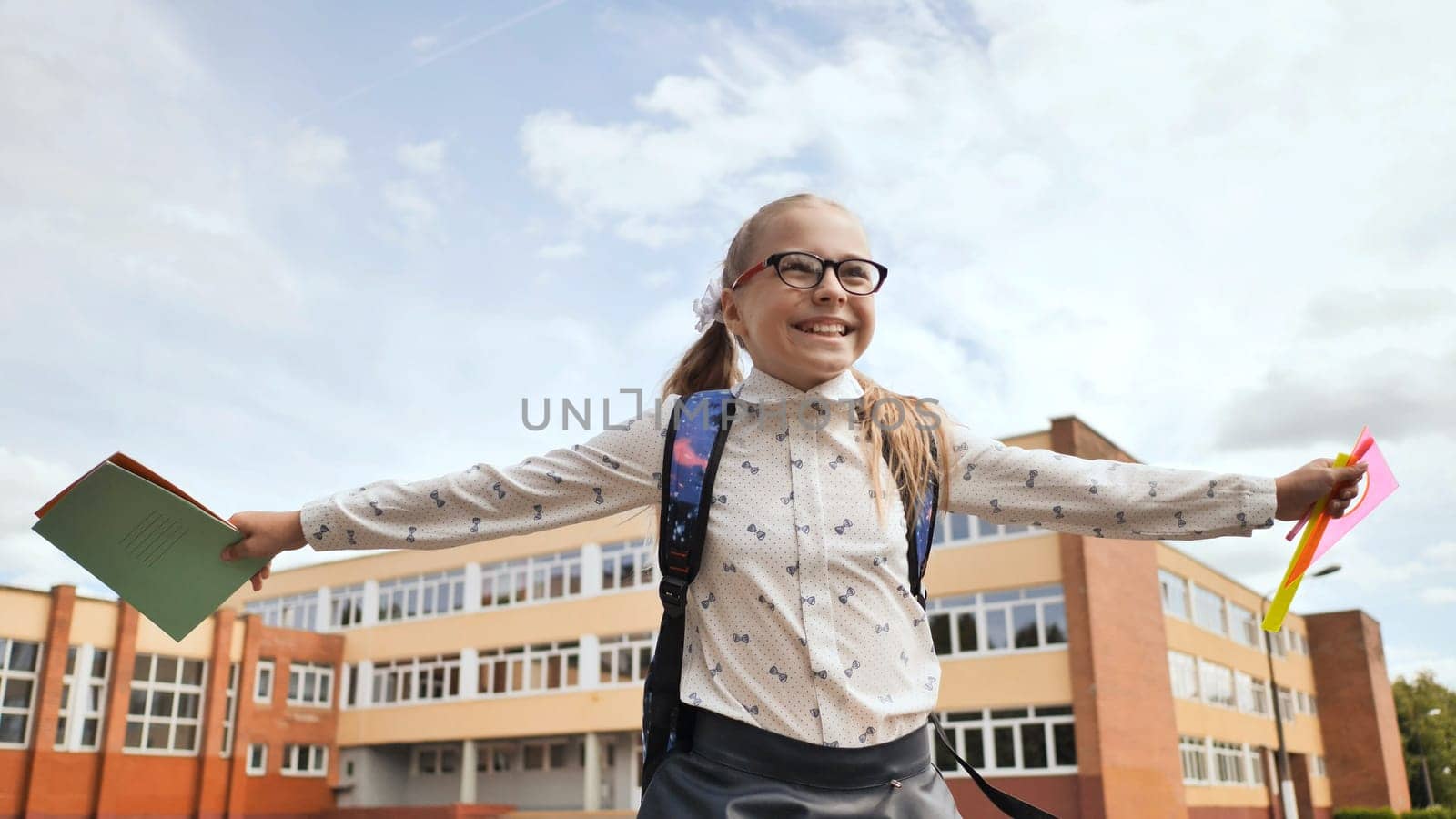 Happy eleven-year schoolgirl runs with a backpack and exercise books after school