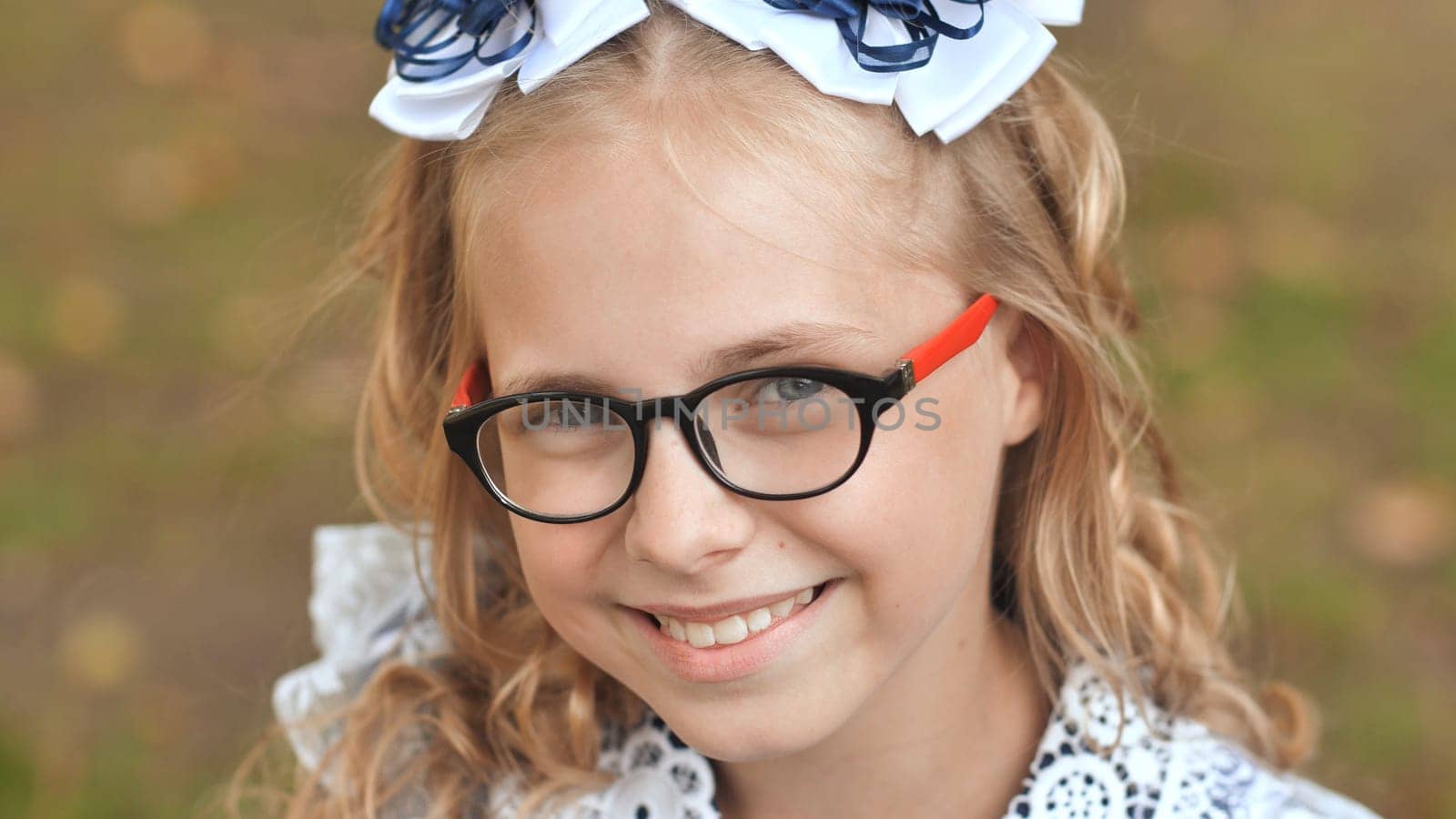 Portrait of a smiling 13 year old blonde girl pulling a bow over her head. Face close up