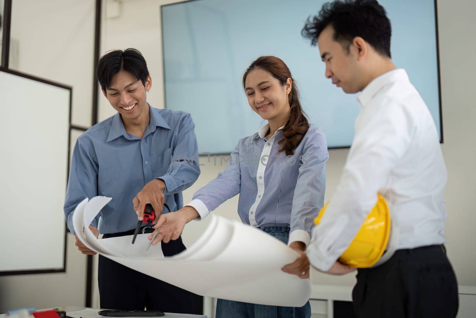 Professionals joyfully participate in a design session, innovating and cutting plans to develop effective building blueprints.