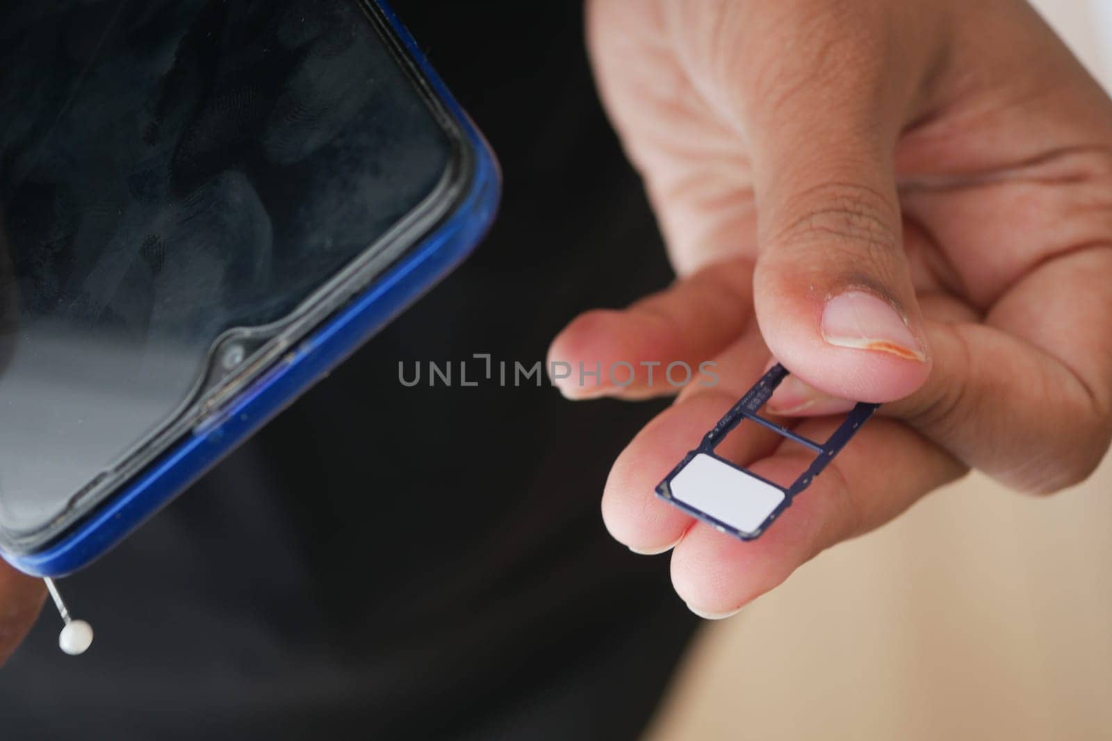 A hand holds a SIM card while preparing to insert it into a smartphone.