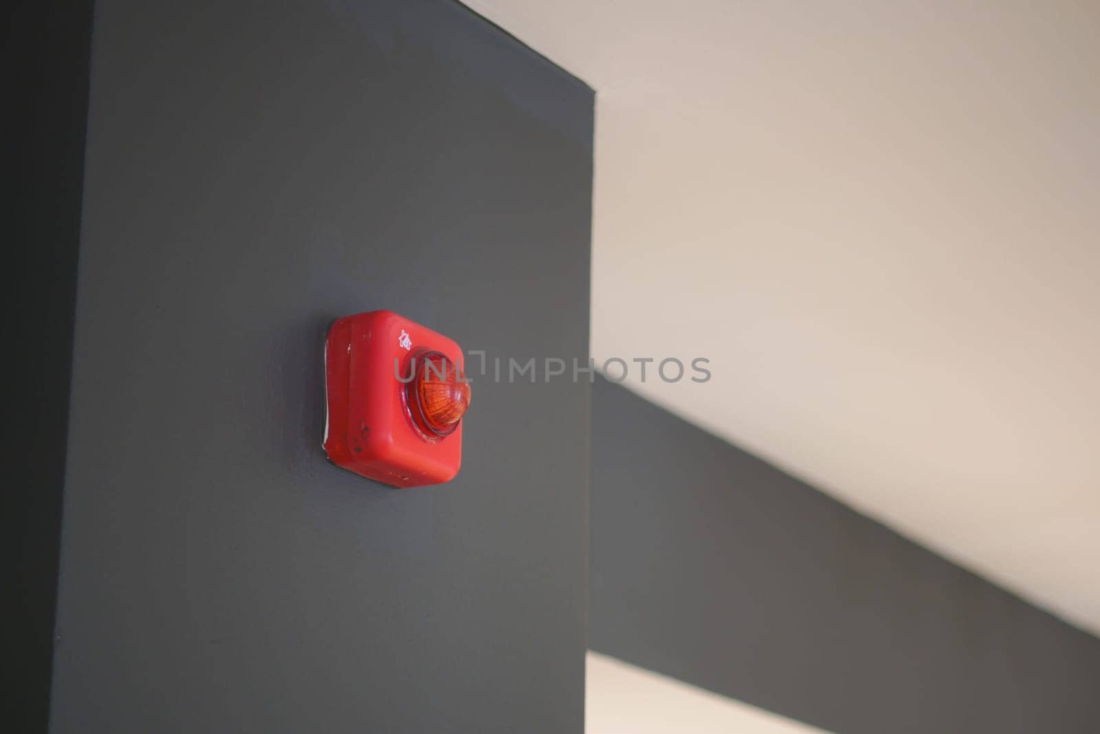 A bright red alarm light mounted on a dark wall enhances safety visuals indoors.