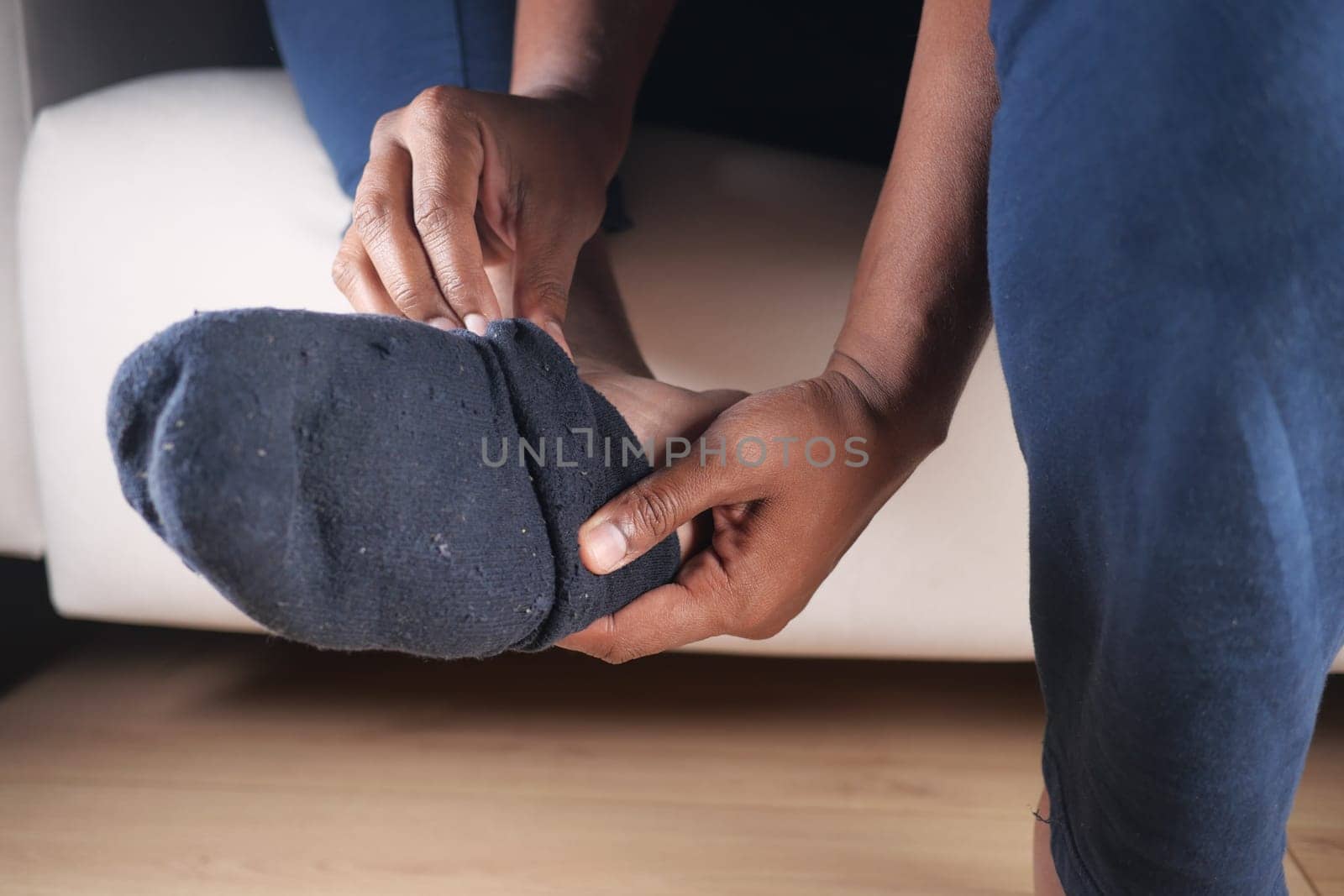 Individual adjusts a sock on their foot while sitting comfortably at home.